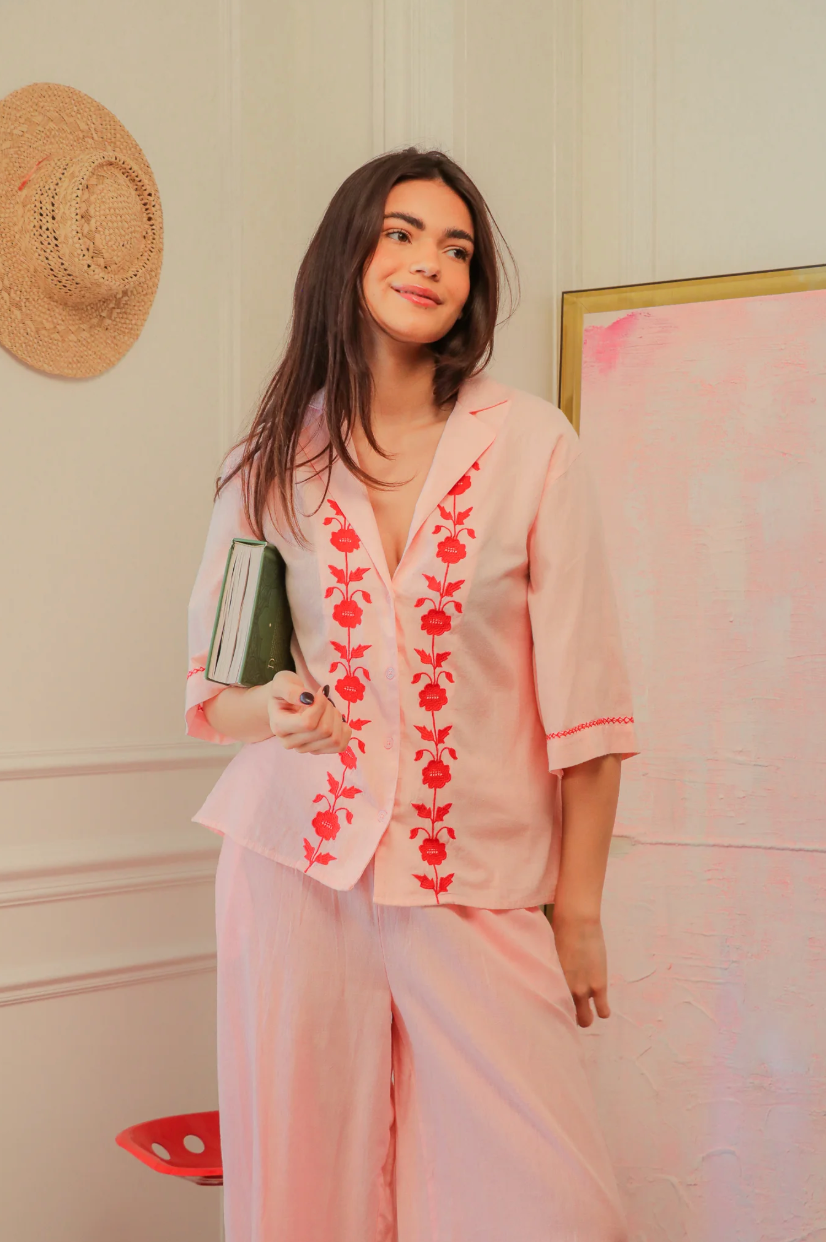 Woman wearing a pink matching outfit with red floral embroidery by The Corner Paris.