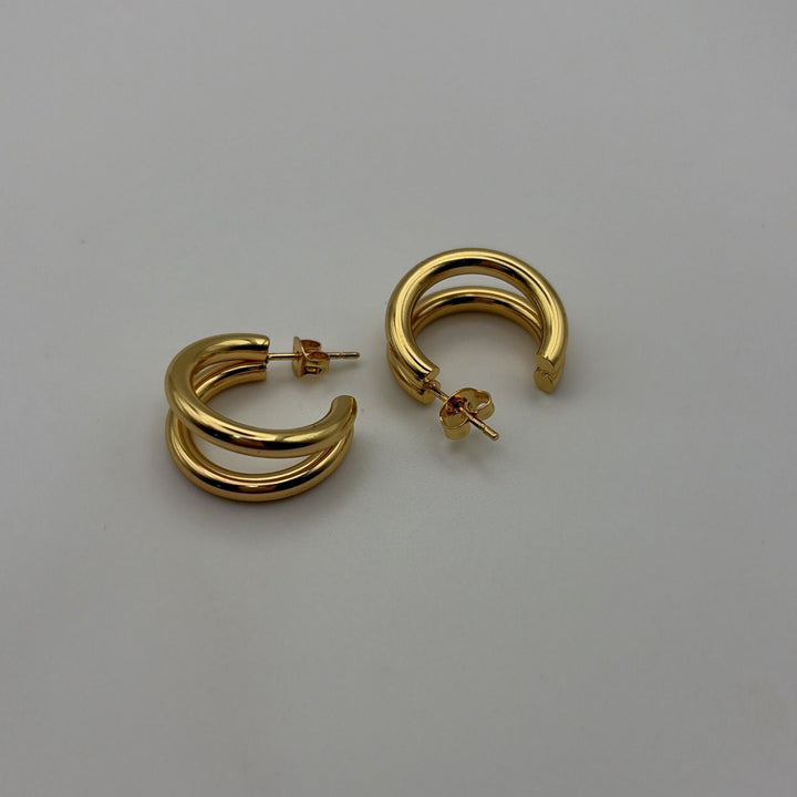 Polished gold double hoop earrings with a modern layered design on a white background