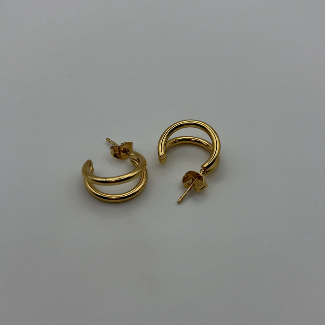 Polished gold double hoop earrings with a modern layered design on a white background