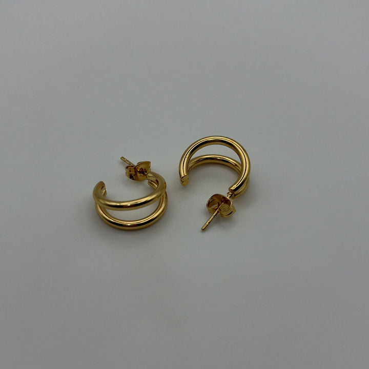 Polished gold double hoop earrings with a modern layered design on a white background