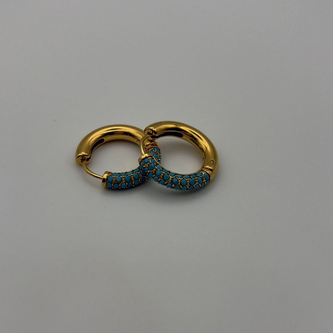 Gold hoop earrings with turquoise stones and polished finish on a white background