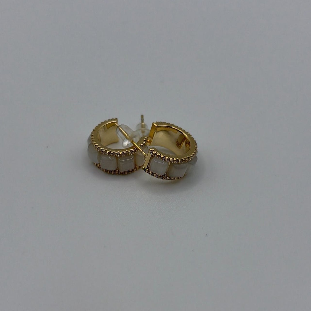 Gold hoop earrings with white stone inlays and elegant polished finish on a white background