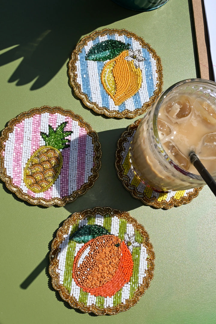Set of four colourful beaded fruit coasters with striped backgrounds and scalloped sequin edges