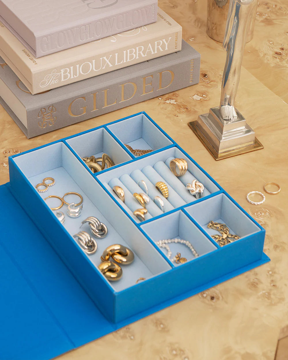 Blue jewellery box with book-inspired design and organised compartments for rings, earrings and necklaces