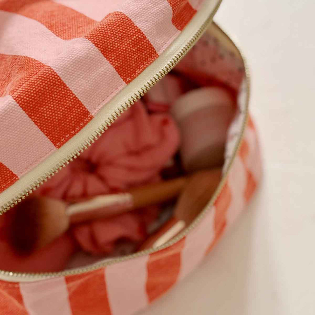 Rose in April Suki Vanity striped cosmetic case in pink and coral with zip closure.